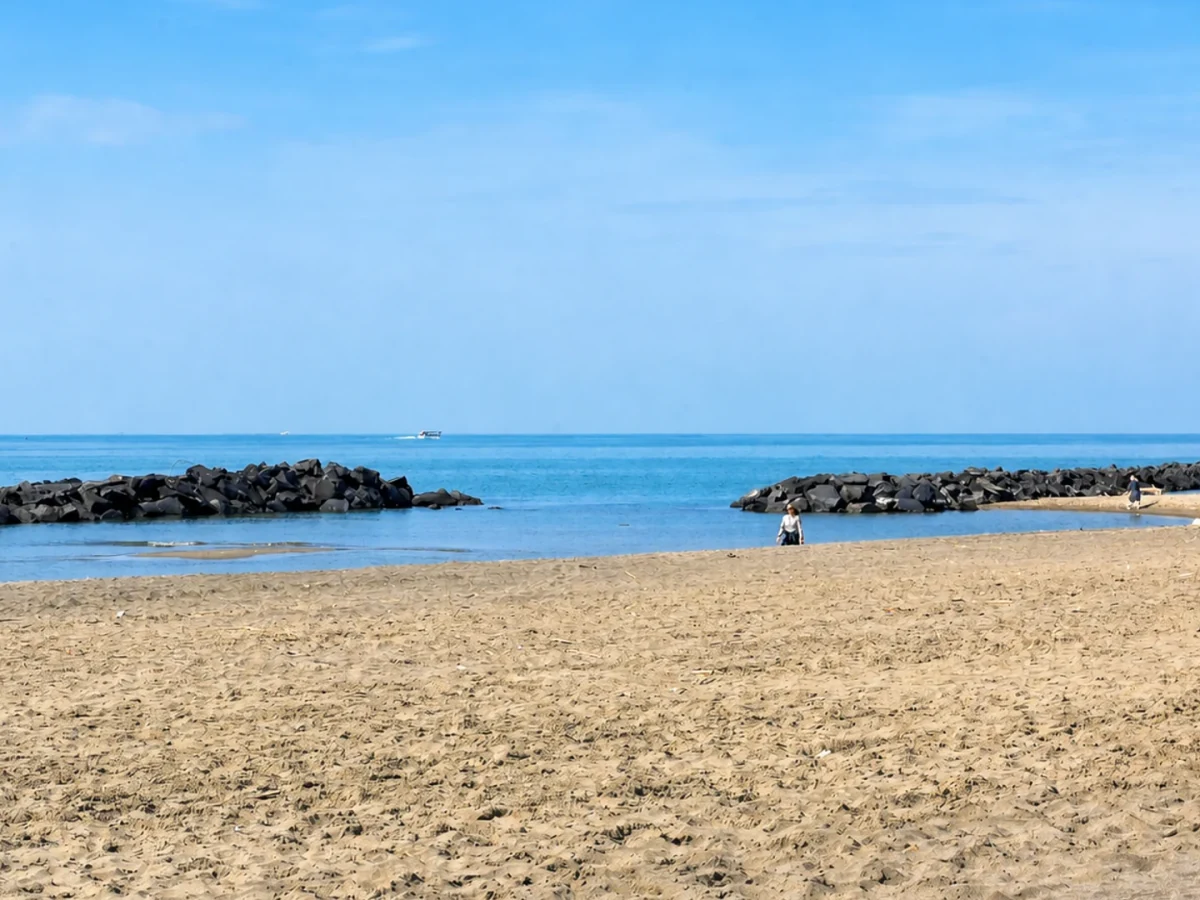 Sandy beach and blue sea in front of Casa dei Venti in Fiumicino